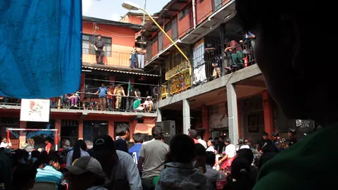 Crowds fill the walkways and the courtyard of a prison block several storeys high. Still from Cocaine Prison.