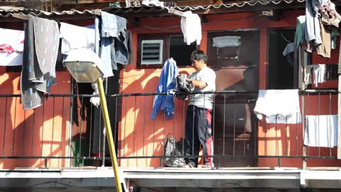 Laundry hangs from a red balcony where a man stands. Still from Cocaine Prison.