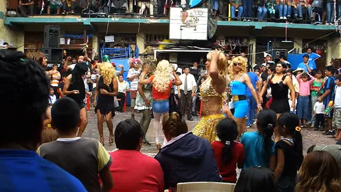 Dancers in bright costumes perform in a prison courtyard while a crowd watches from the balconies. Still from Cocaine Prison.