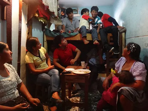 A family sits at a table in a small room crowded with people. Still from Cocaine Prison.