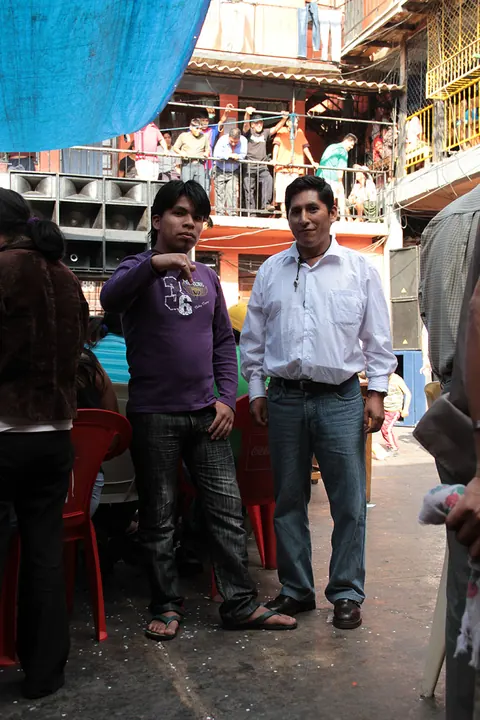 Two men stand talking in a prison courtyard below crowded balconies. Still from Cocaine Prison.