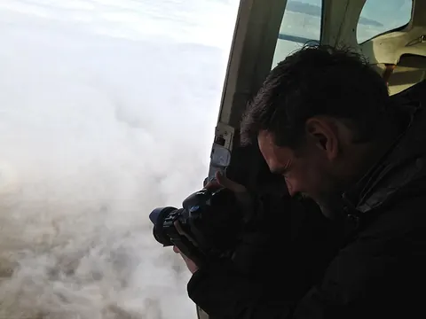 A cameraman films out of an open plane door above the clouds. Still from Cocaine Prison.