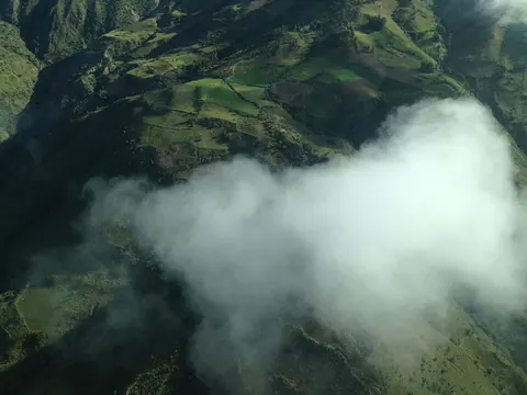 Clouds over green mountains, seen from the air. Still from Cocaine Prison.