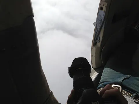 A camera points out of an open plane door into the clouds. Still from Cocaine Prison.