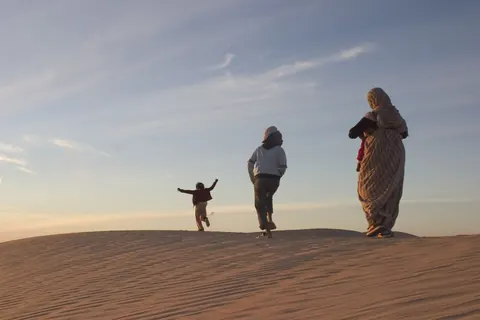 Three figures walk along the crest of a sand dune. Still from Stolen.