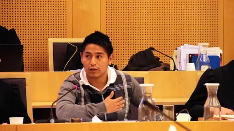 A young man speaks into a microphone at a courtroom table. Still from The Bolivian Case.