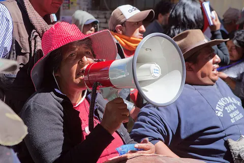 A woman in a pink hat shouts into a megaphone among protesters. Still from The Fight.