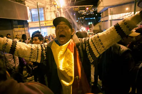 A man in a woven jacket shouts with his arms wide open at night. Still from The Fight.