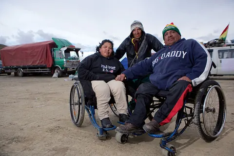 Three people pose with their wheelchairs beside a highway. Still from The Fight.