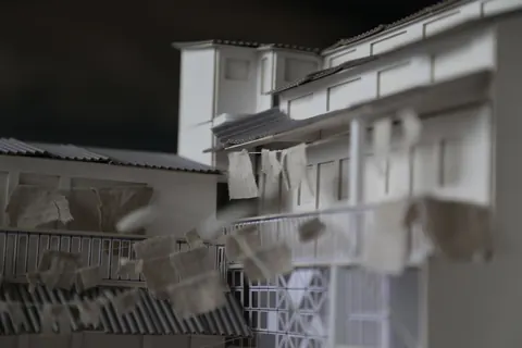 A grey 3D model of a prison building with laundry hanging from it. From Prison X.